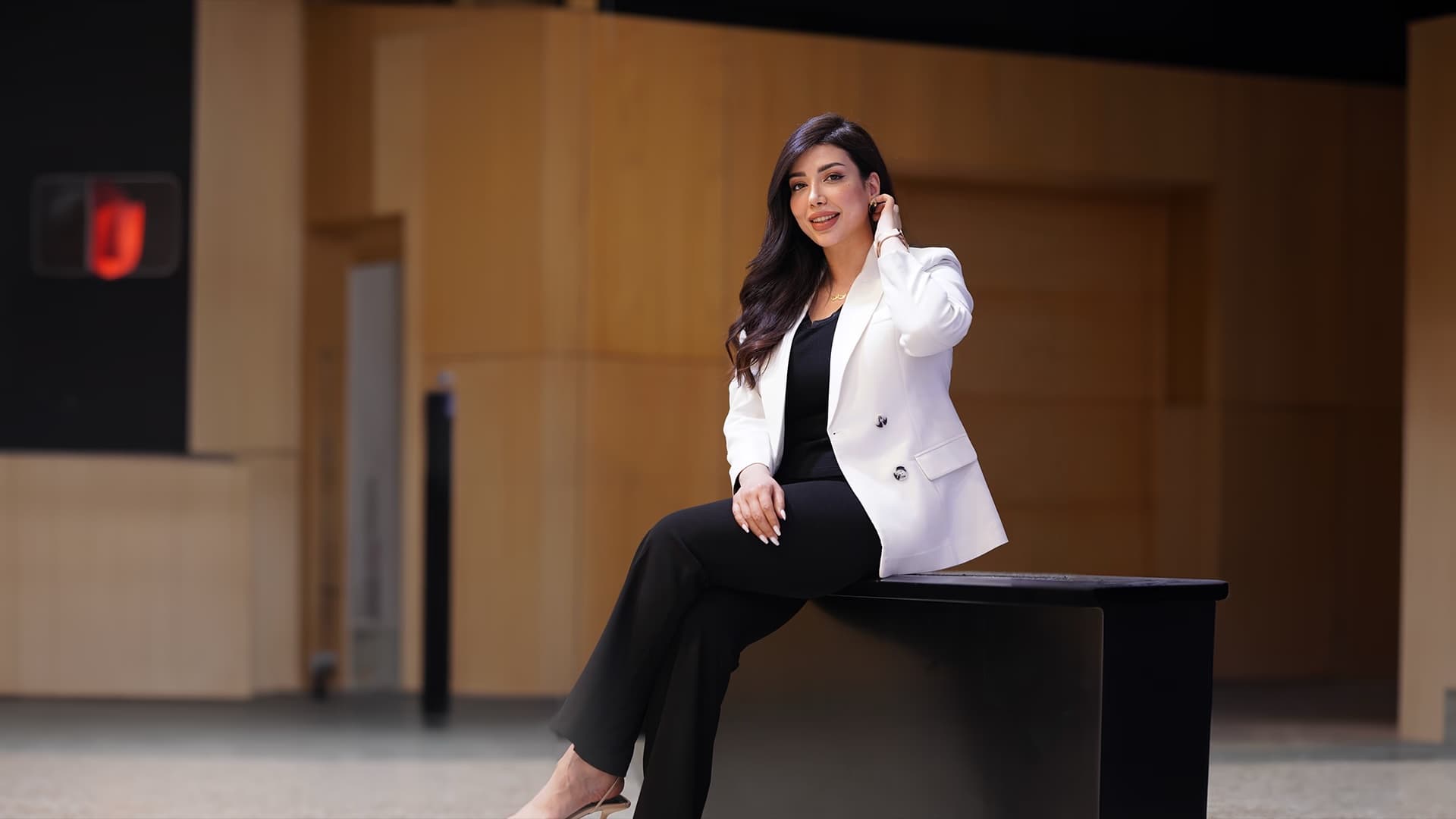 Walaa Mutar seated in a lobby, wearing a white blazer